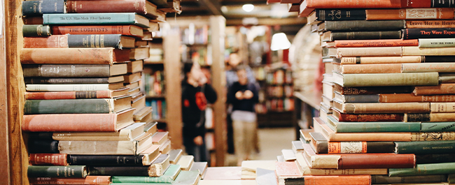 library books arranged to form a gap in the shape of a circle through which students can be seen in the background